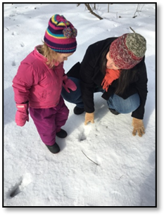 child and teacher playing in the snow